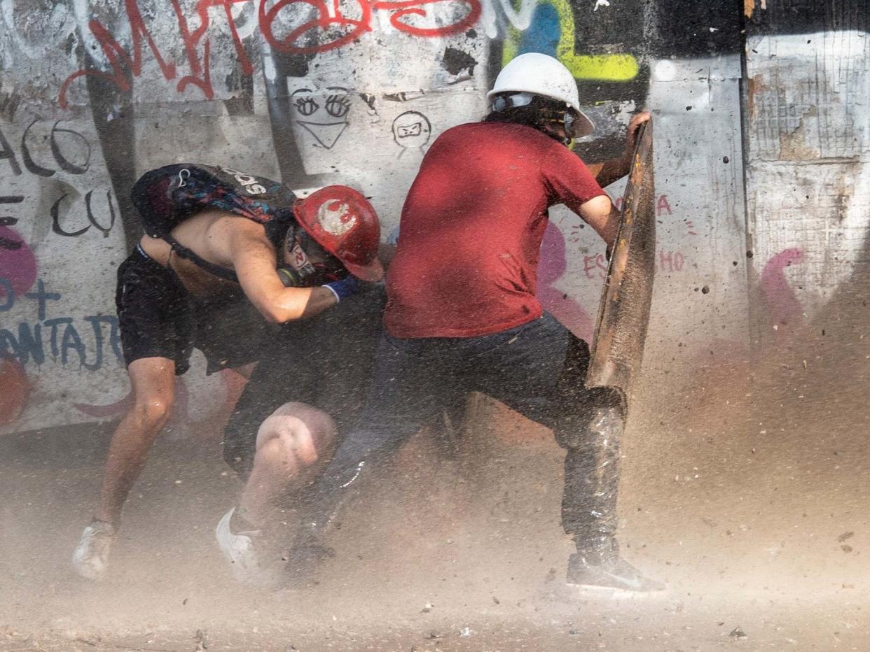 Demonstrators take cover as they clash with riot police during a protest against the government: AFP/Getty