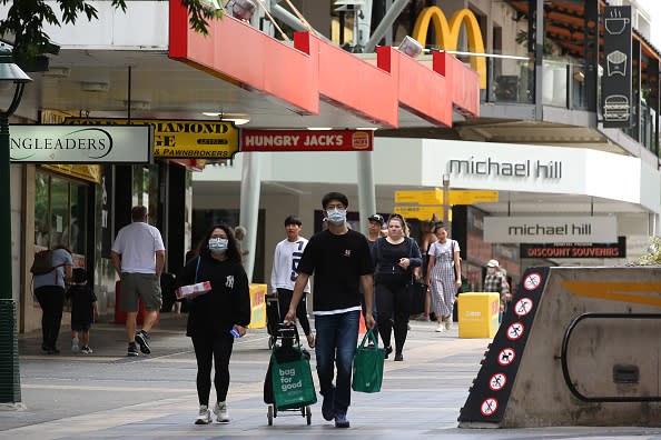 People wearing masks walk through the Brisbane CBD.