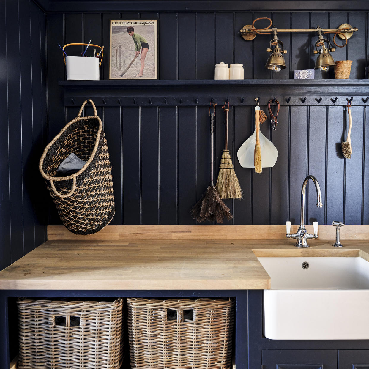  Utility room with navy wall panelling, oak counter and rattan baskets. 