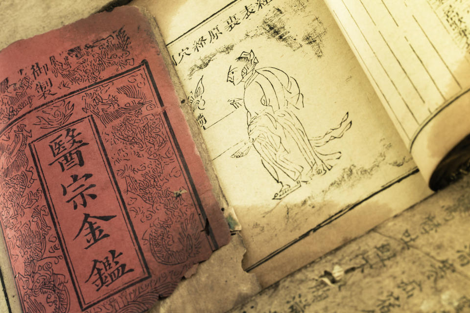 Ancient Chinese medicine book open to a detailed illustration and text, showcasing traditional practices and historical art