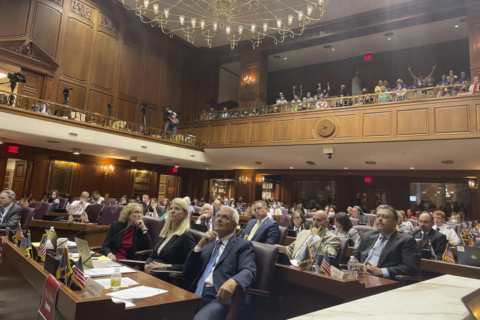 Indiana House committee members listen to testimony on its version of a Senate-approved abortion ban as listeners in an upstairs gallery of the Indiana House chamber in Indianapolis, Tuesday, Aug. 2, 2022, indicate their support. (AP Photo/Arleigh Rodgers)