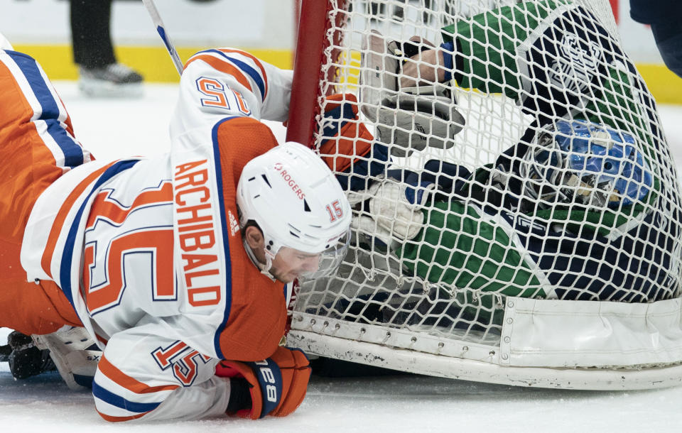 Edmonton Oilers right wing Josh Archibald (15) crashes into Vancouver Canucks goaltender Thatcher Demko (35) and the goal during the first period of an NHL hockey game Thursday, Feb. 25, 2021, in Vancouver, British Columbia. (Jonathan Hayward/The Canadian Press via AP)