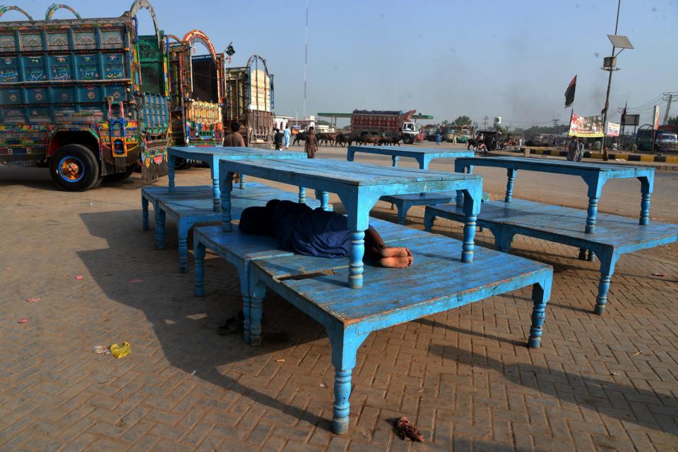 A truck driver takes a nap under stacked tables in the blazing heat in Jacobabad, Pakistan.