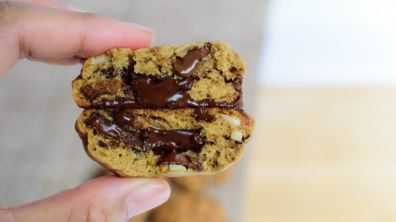 gooey chocolate-filled cookies between fingers