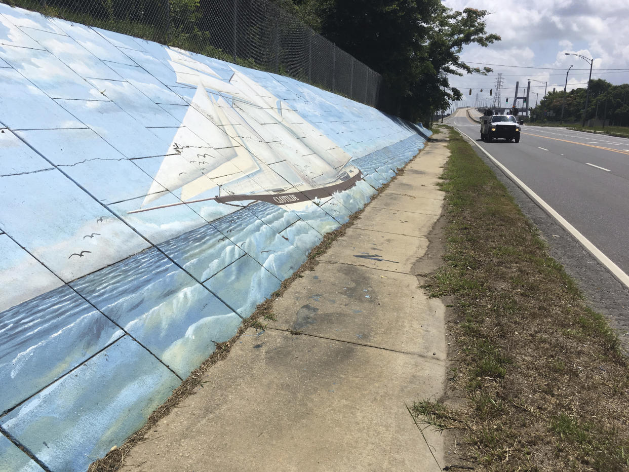 Traffic passes a mural of the Clotilda along Africatown Boulevard in Mobile, Ala.. (AP Photo/Kevin McGill)