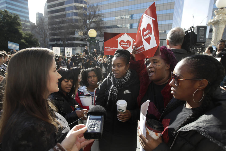 Oakland Mayor Libby Schaaf, left, talks with Misty Cross, second from left, Tolani King, center, Sharena Thomas, second from right, and Dominique Walker, all from the group Moms 4 Housing, at a rally outside of City Hall in Oakland, Calif., Tuesday, Jan. 7, 2020. Some California lawmakers said they support a group of homeless women who have been illegally living in a vacant three-bedroom house since November, partly to protest real estate speculators who drive up housing costs in the pricey San Francisco Bay Area. (AP Photo/Jeff Chiu)