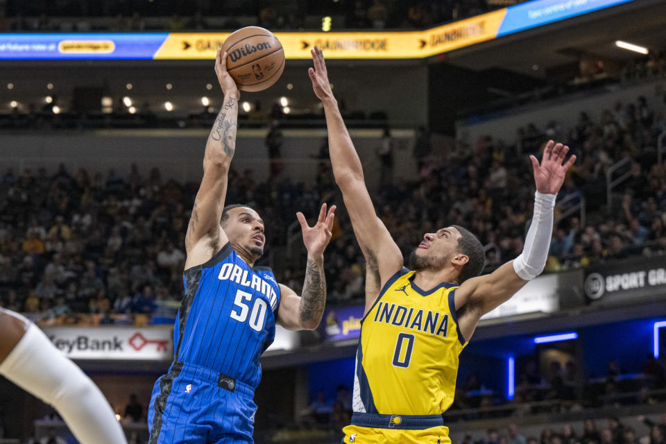 Orlando Magic guard Cole Anthony (50) shoots while defended by Indiana Pacers guard Tyrese Haliburton (0) during the first half of an NBA basketball game in Indianapolis, Sunday, Nov. 19, 2023. (AP Photo/Doug McSchooler)
