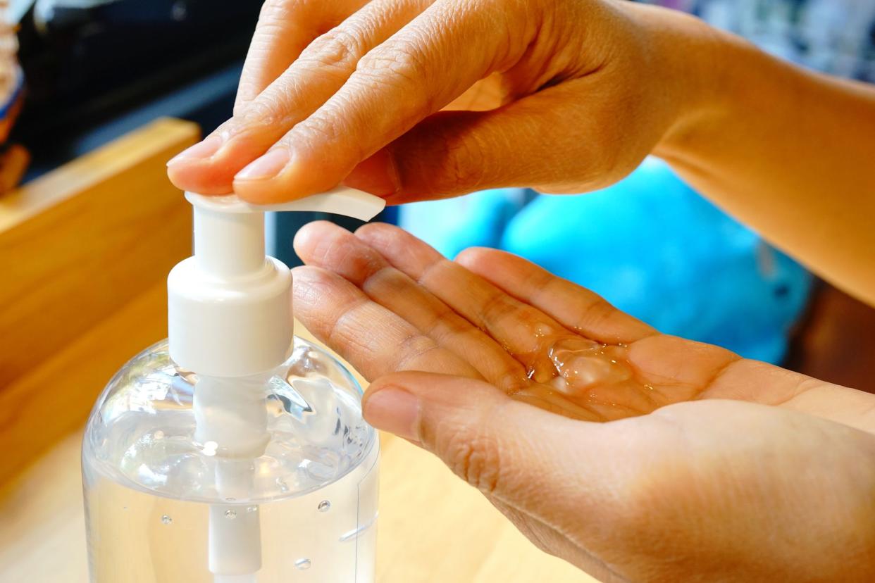 Hands using hand sanitizer gel pump dispenser