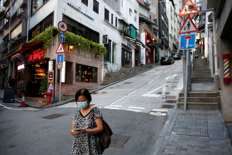 FILE PHOTO: A woman wears a surgical mask while walking at Central following the coronavirus disease (COVID-19) outbreak in Hong Kong,