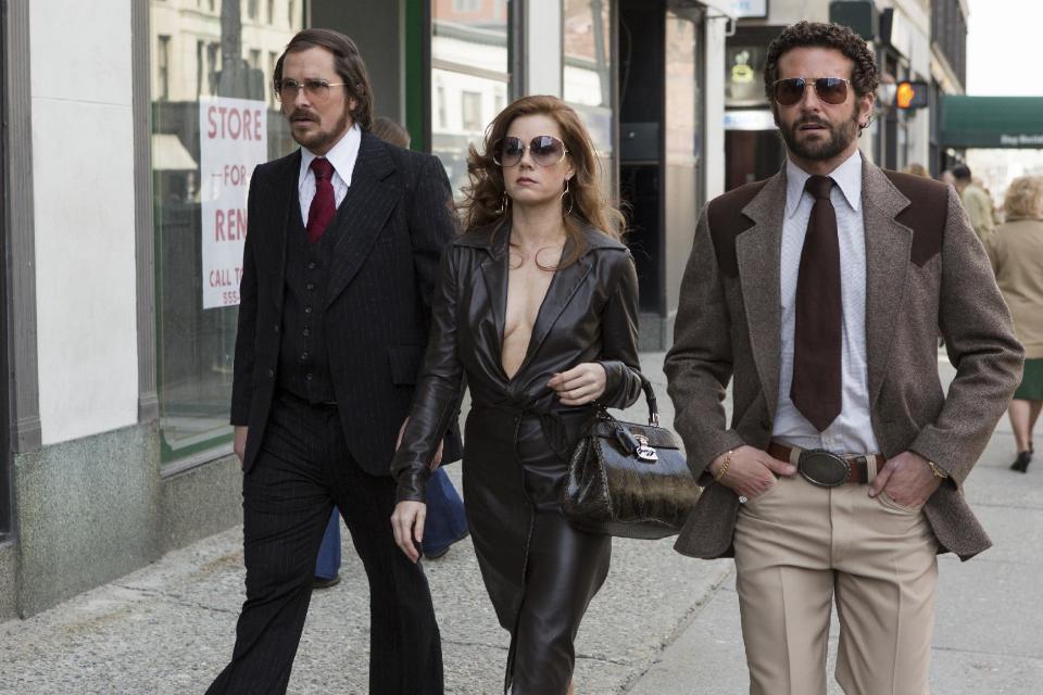 In this photo released by Sony Picturess, Christian Bale, left, as Irving Rosenfeld, Amy Adams as Sydney Prosser, center, and Bradley Cooper as Richie Dimaso walk down Lexington Avenue in a scene from Columbia Pictures' film, "American Hustle." Rosenfeld rocks an elaborate comb-over, complete with fuzzy, glue-on hairpiece. Adams' dress is vintage Halston. For accessories, her glasses are vintage Christian Dior, her handbag is Gucci, and shoes are vintage. Bale's suit, tie, shirt, and glasses are vintage. Cooper's suit, tie shirt, belt, and glasses are vintage. (AP Photo/Sony - Columbia Pictures, Francois Duhamel)