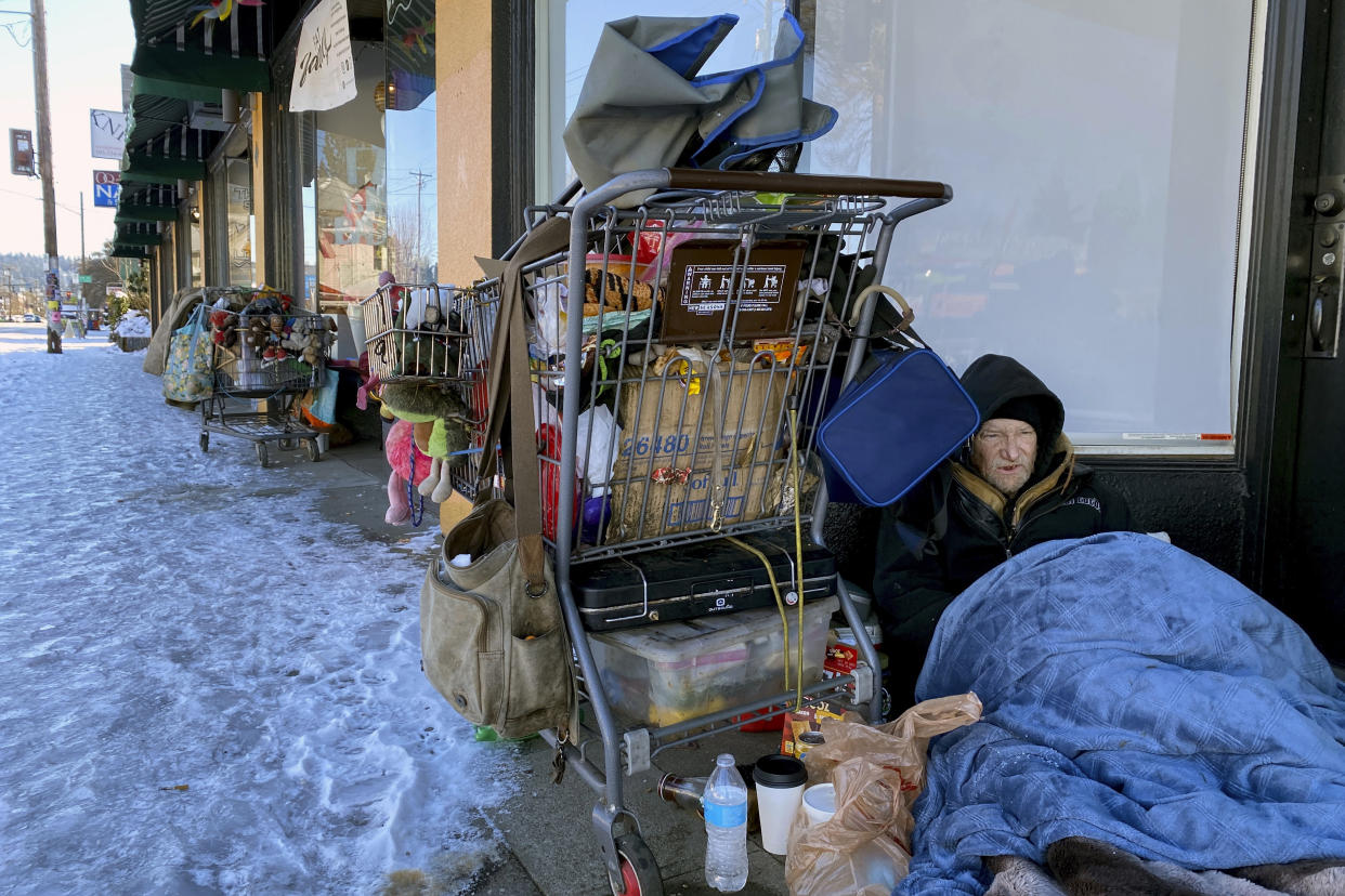 Tim Varner, 57, uses blankets to stay warm in the snow as he huddles with his belongings in a storefront in Portland, Ore. on Friday, Feb. 24, 2023. The thousands of people living on Portland's streets have struggled to stay warm after a storm on Wednesday dumped nearly a foot of snow, resulting in the city's second snowiest day on record. (AP Photo/Claire Rush)
