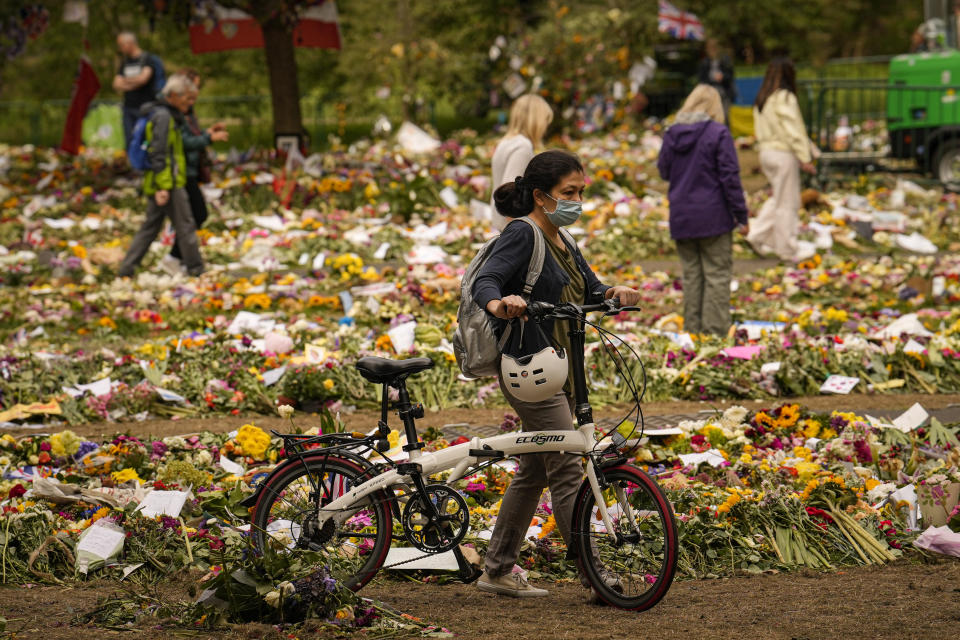 People bring floral tributes to Queen Elizabeth II, the day after her funeral in London's Green Park, Tuesday, Sept. 20, 2022. The Queen, who died aged 96 on Sept. 8, was buried at Windsor alongside her late husband, Prince Philip, who died last year. (AP Photo/Vadim Ghirda)