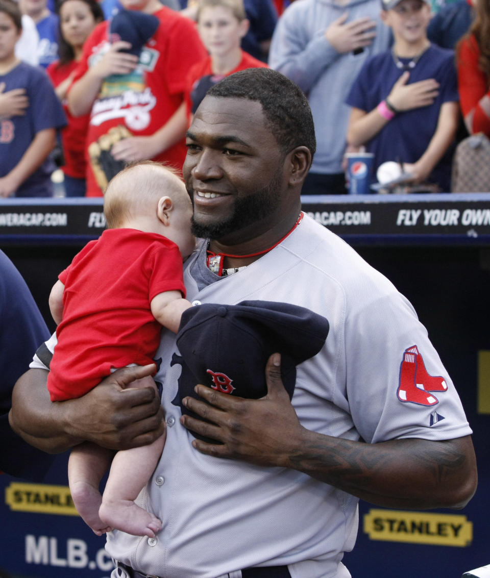 Boston Red Sox' David Ortiz holds a fan's baby during the national anthem before their baseball game against the Kansas City Royals at Kauffman Stadium in Kansas City, Mo., Thursday, Aug. 8, 2013. (AP Photo/Colin E. Braley)