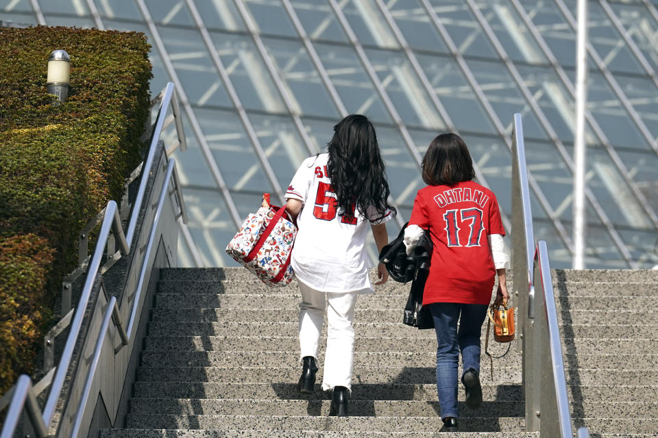 Fans of Japan's Shohei Ohtani walk toward the Tokyo Dome prior to the Pool B game between Japan and China at the World Baseball Classic (WBC) at the Tokyo Dome Thursday, March 9, 2023, in Tokyo. Japanese baseball player Shohei Ohtani is arguably the game's best player. But he's more than just a baseball player. He's an antidote for many in his native country. (AP Photo/Eugene Hoshiko)