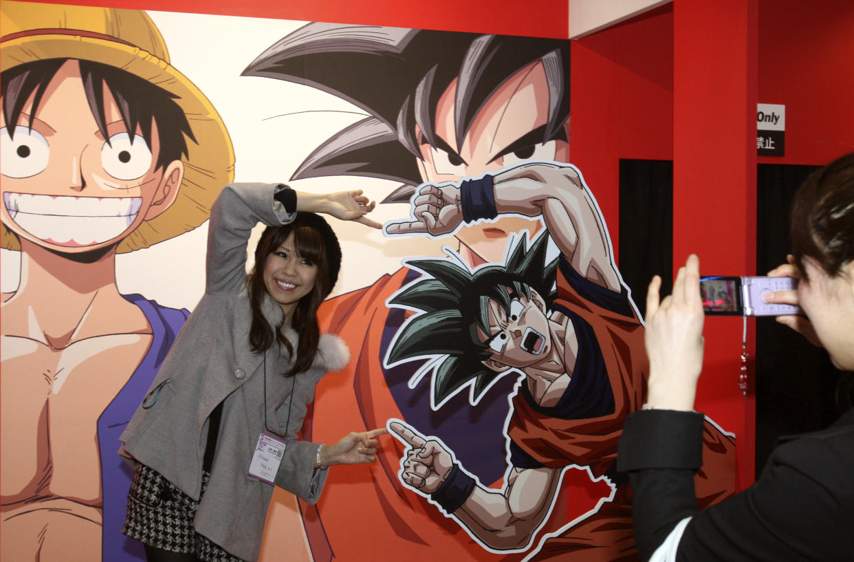 A visitor poses with Son Goku, the main character of Japan's popular manga series Dragon Ball, for a snap during the business day of Tokyo International Anime Fair 2010 in Tokyo, Japan, Thursday, March 25, 2010. More than 200 anime-related companies and organizations gathered in this annual event that opens to public on March 27 and 28. (AP Photo/Koji Sasahara)