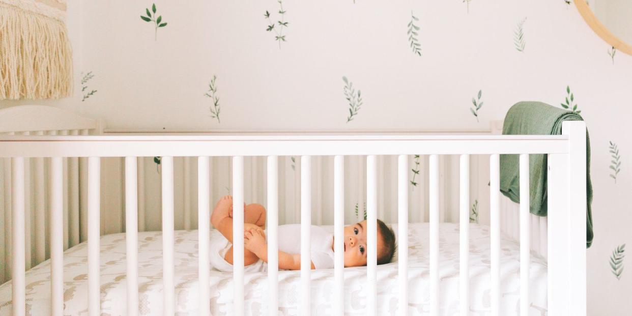 baby in white crib in boho nursery