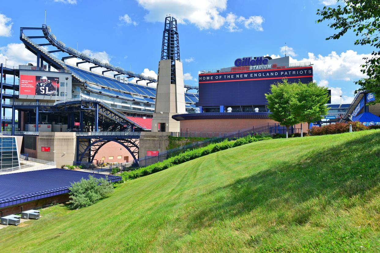 New England Patriots, Gillette Stadium, Foxborough, Massachusetts, exterior with grass in the foreground, empty seats, dramatically against a blue sky with white clouds