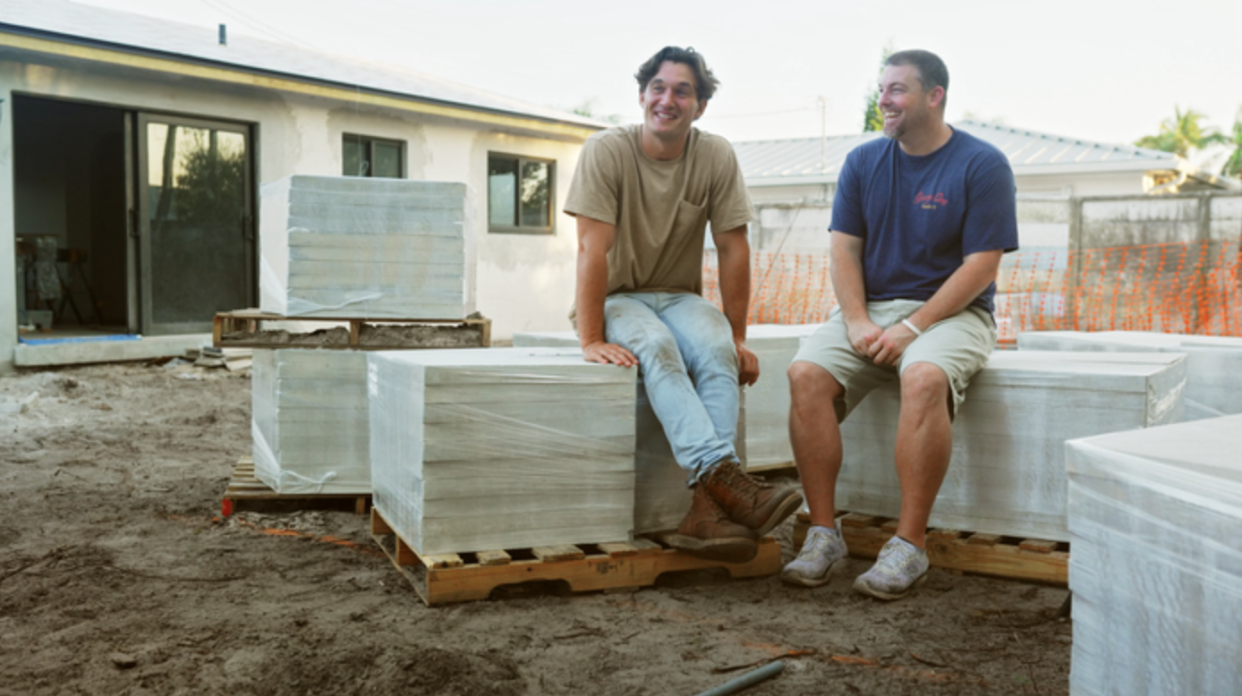 a couple of men sitting on a stack of wood