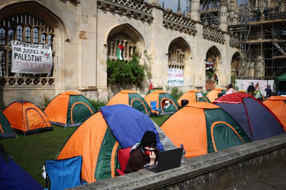 A person works on a laptop computer as they sit by tents during a protest in support of Palestinian people, at King’s College at Cambridge (AFP via Getty)