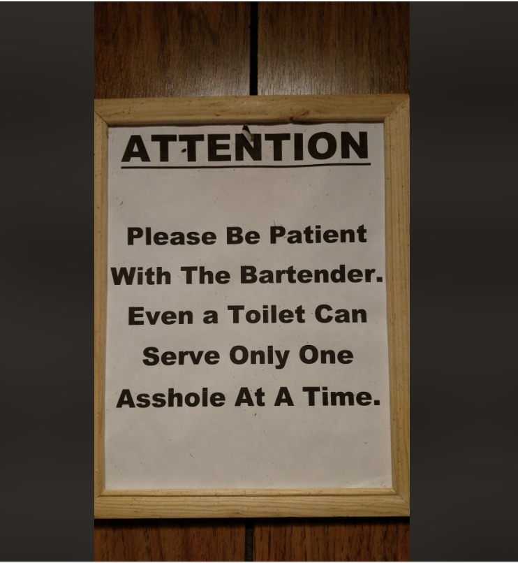 Sign reads: “Attention. Please be patient with the bartender. Even a toilet can serve only one asshole at a time.”