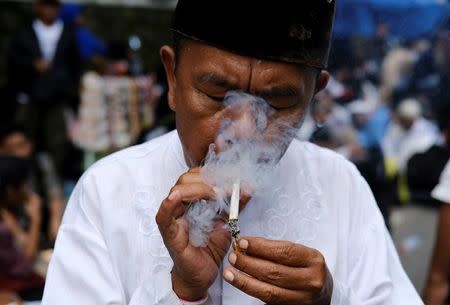 Indonesian Muslim Muhammad Paijo smokes his cigarette during a protest near South Jakarta court in Jakarta, Indonesia, May 9, 2017. REUTERS/Beawiharta/Files