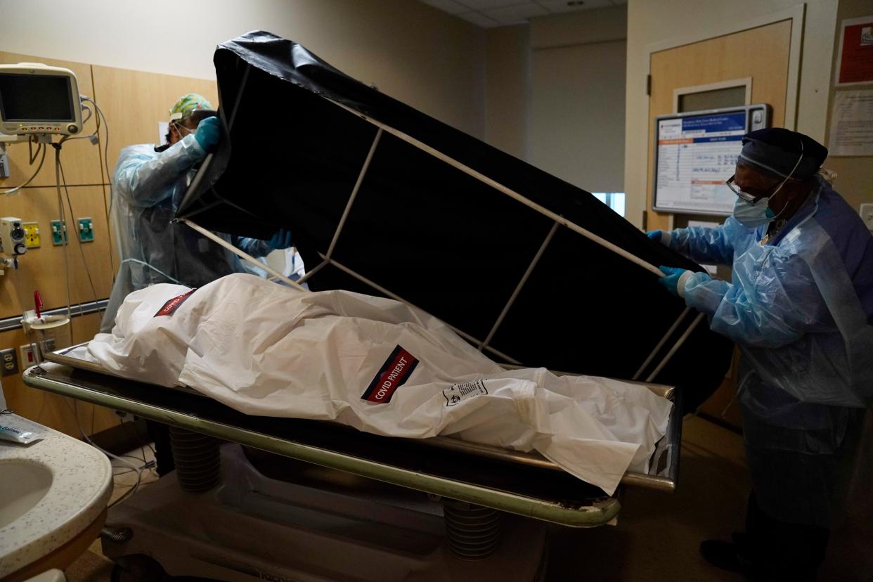 FILE - In this Jan. 9 photo, transporters Miguel Lopez, right, Noe Meza prepare to move a body of a COVID-19 victim to a morgue at Providence Holy Cross Medical Center in the Mission Hills section of Los Angeles. 