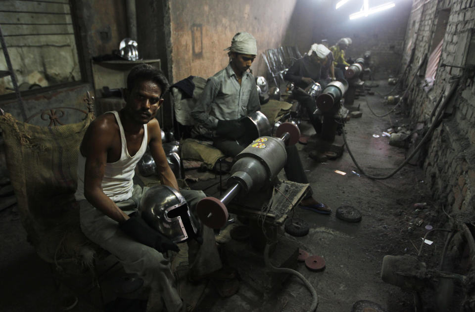 In this, June 2, 2012 photograph, workers polish helmets being prepared for a Hollywood period movie at a workshop owned by Indian businessman Ashok Rai, unseen, in Sahibabad, India. From Hollywood war movies to Japanese Samurai films to battle re-enactments across Europe, Ashok Rai is one of the world's go-to men for historic weapons and battle attire. (AP Photo/Saurabh Das)