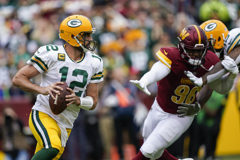 Green Bay Packers quarterback Aaron Rodgers (12) scrambles away from Washington Commanders defensive end James Smith-Williams (96) during the first half of an NFL football game Sunday, Oct. 23, 2022, in Landover, Md. (AP Photo/Susan Walsh)