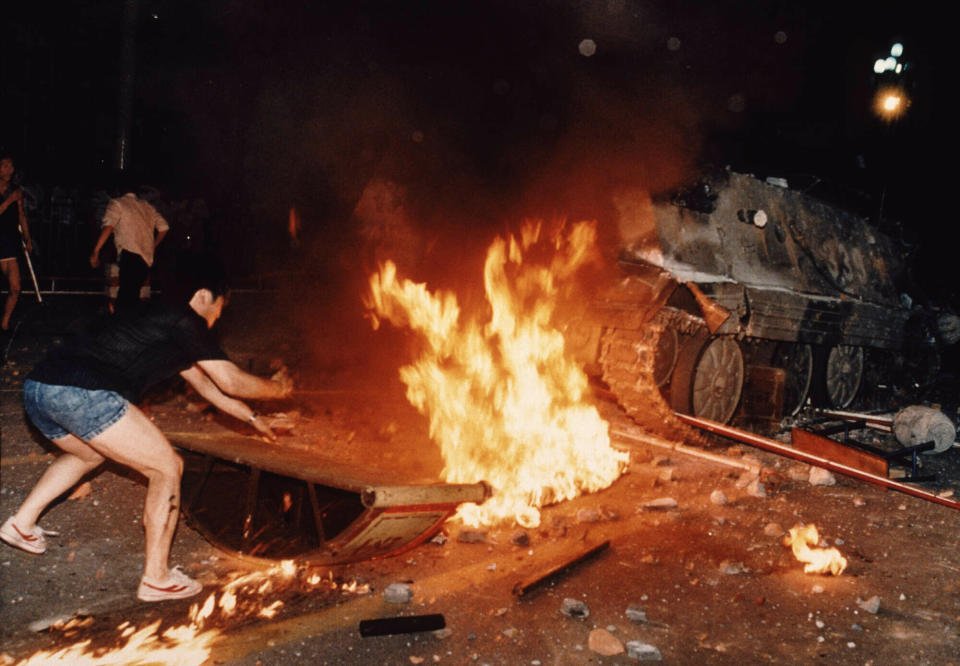 FILE - In this June 4, 1989 file photo, a student protester puts barricades in the path of an already burning armored personnel carrier that rammed through student lines during an army attack on anti-government demonstrators in Beijing's Tiananmen Square. A government soldier who escaped the armored vehicle was killed by demonstrators. Over seven weeks in 1989, student-led pro-democracy protests centered on Beijing’s Tiananmen Square became China’s greatest political upheaval since the end of the Cultural Revolution more than a decade earlier. Next week marks the 30th anniversary of the bloody crackdown that ended the protest. (AP Photo/Jeff Widener, File)