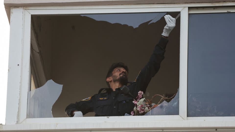 An investigator inspects a damaged window of a building at the site of an explosion in Tel Aviv on July 19, 2024. - Ricardo Moraes/Reuters