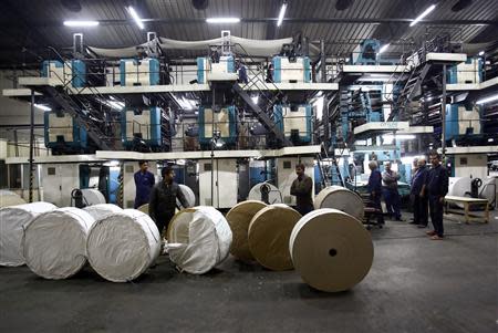 Employees move paper rims to load them onto a printing machine inside the Dainik Jagran printing press in Noida, on the outskirts of New Delhi February 25, 2014. REUTERS/Anindito Mukherjee