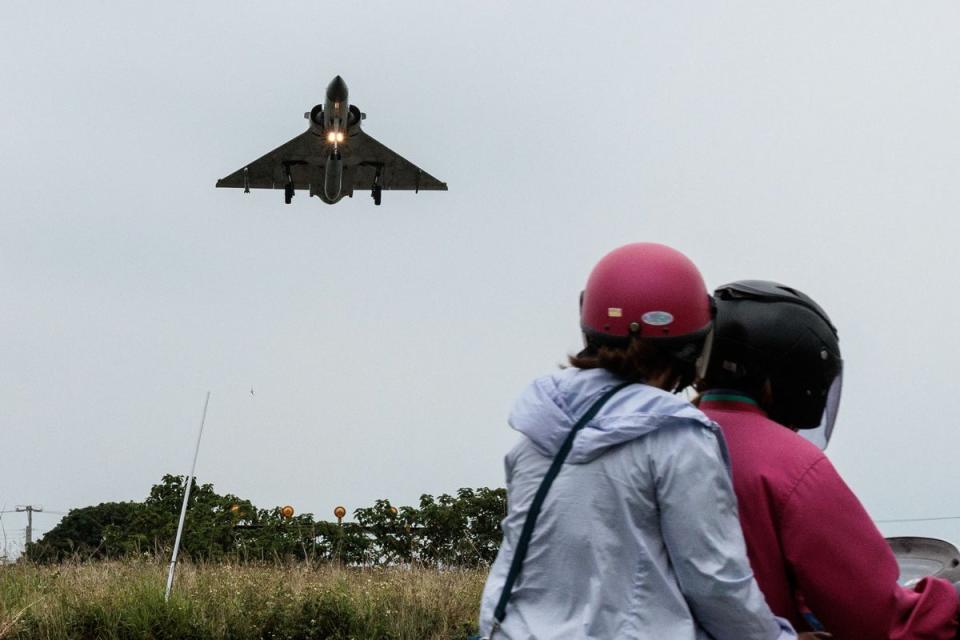 Two people ride a motorcycle as a Taiwanese Air Force Mirage 2000 fighter jet approaches for landing in northern Taiwan (AFP via Getty Images)