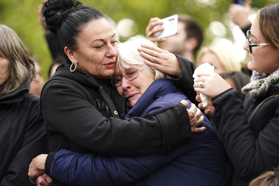 Two women hug amid a crowd.