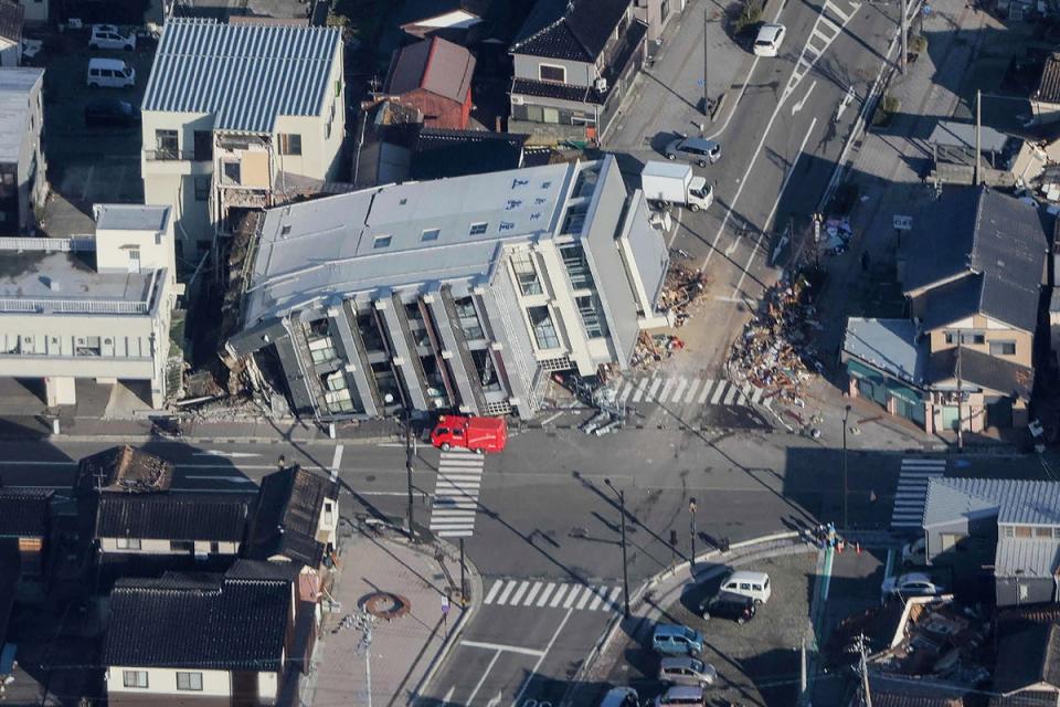 A rescue vehicle (C) parked next to a seven-storey building which fell over in Wajima, Ishikawa prefecture (JIJI PRESS/AFP via Getty Images)