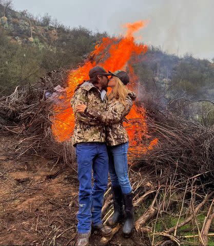 <p>Ryan Bingham Instagram</p> Ryan Bingham and Hassie Harrison kiss in front of a fire