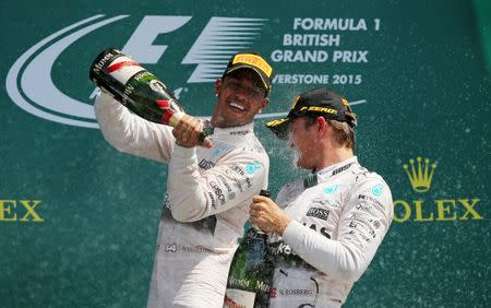 Formula One - F1 - British Grand Prix 2015 - Silverstone, England - 5/7/15 Mercedes' Lewis Hamilton celebrates his win on the podium with the champagne and Mercedes' Nico Rosberg Reuters / Paul Childs