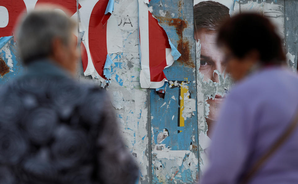 Women walk past a poster showing Spain’s Socialist Party (PSOE) leader Sanchez in Lugones