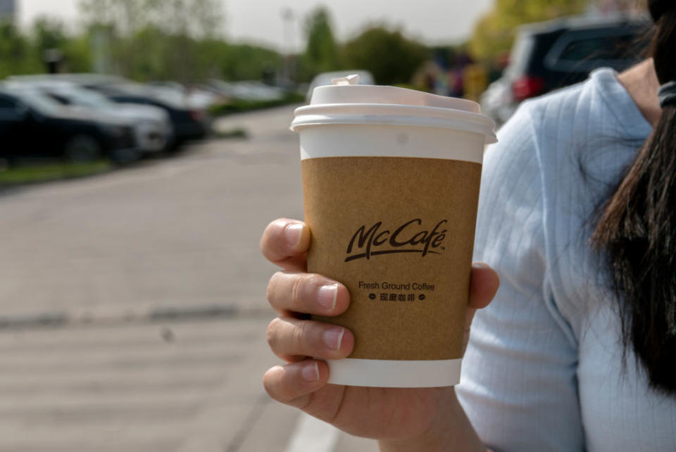 A girl holds a McCafe coffee cup. 