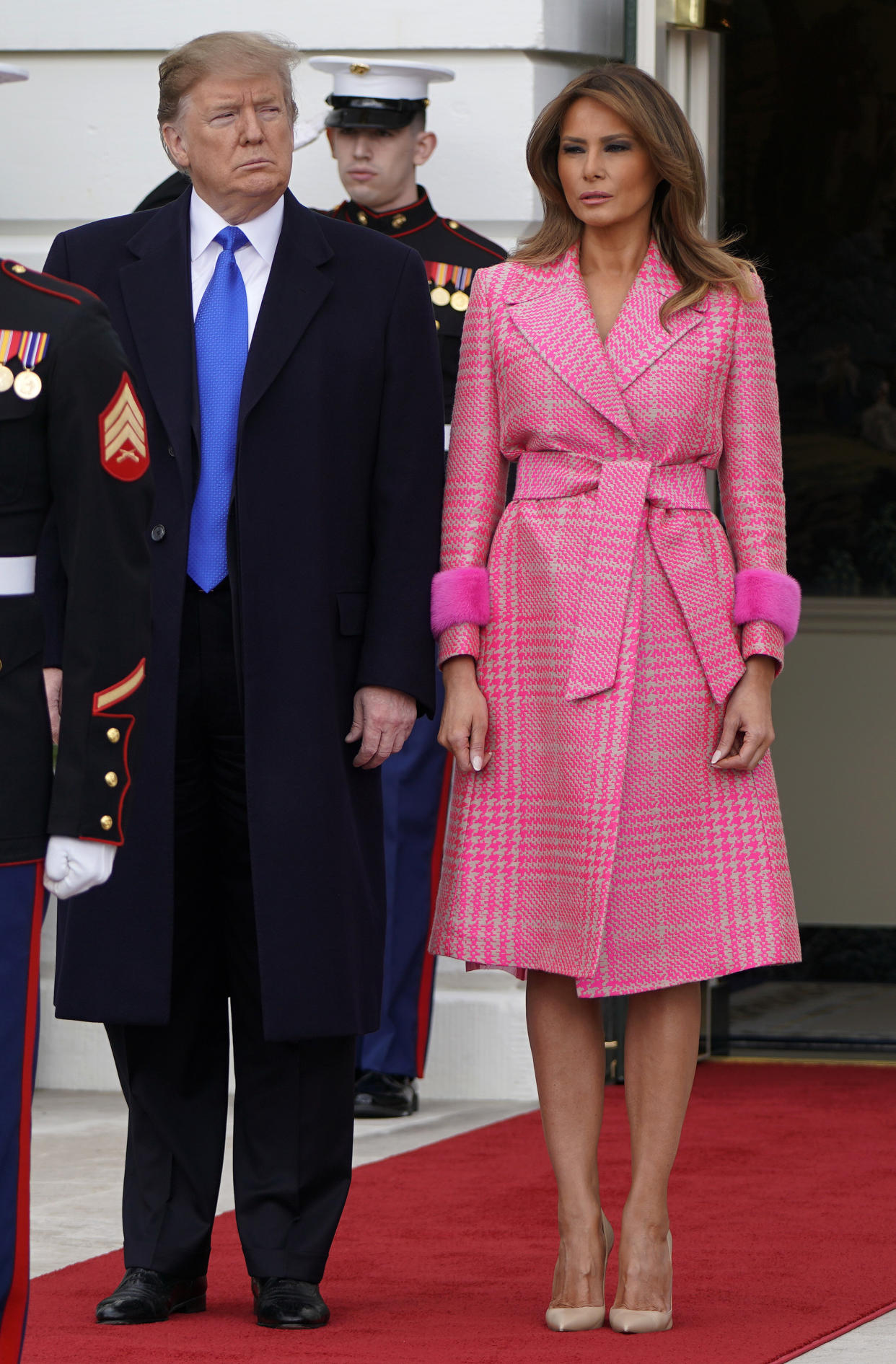 Melania Trump stands beside the president in a pink Fendi coat. (Photo: Getty Images)