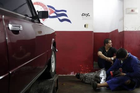 Mechanics work on a piece of a Lada in a car shop in Havana February 9, 2015. REUTERS/Enrique De La Osa