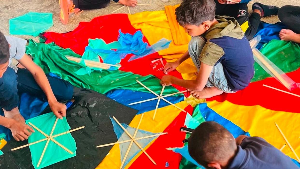 PHOTO: AFSC volunteers help children make kites for the festival in Rafah. (American Friends Service Committee)