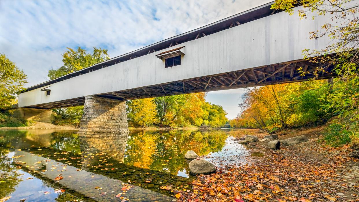 Potter's Covered Bridge crosses the West Fork of the White River surrounded by colorful fall foliage in Noblesville, Indiana.