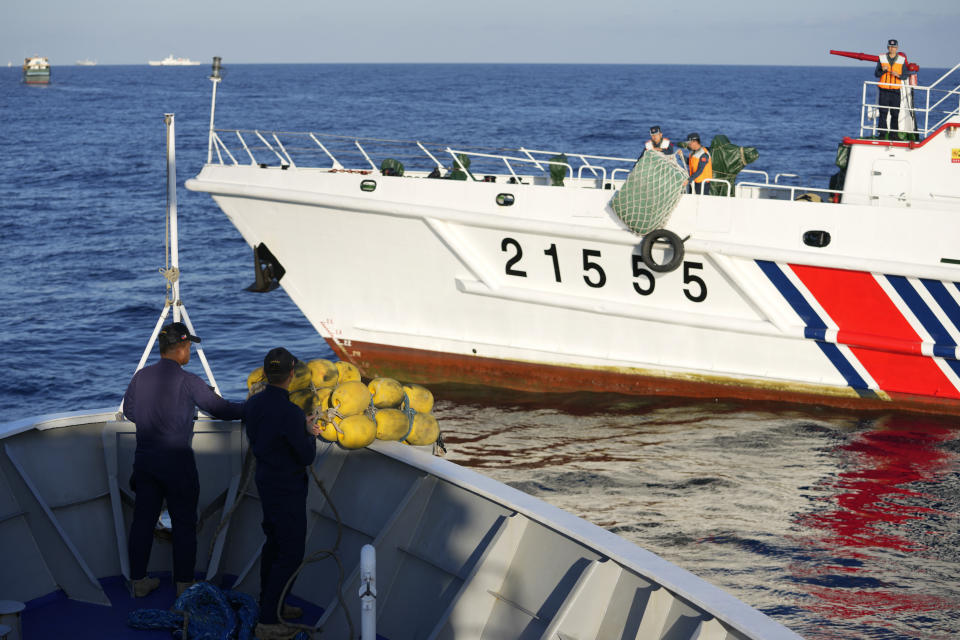 FILE - Crew members of Philippine coast guard BRP Sindangan prepare rubber fenders as a Chinese coast guard ship tries to block it's path while they tried to enter the Second Thomas Shoal, locally known as Ayungin Shoal, in the disputed South China Sea Tuesday, March 5, 2024. The first-ever trilateral summit between President Joe Biden, Japanese Prime Minister Kishida and Philippine President Ferdinand Marcos Jr. comes as the Philippines faces escalating maritime tension with China over their contested South China Sea claims. (AP Photo/Aaron Favila, File)