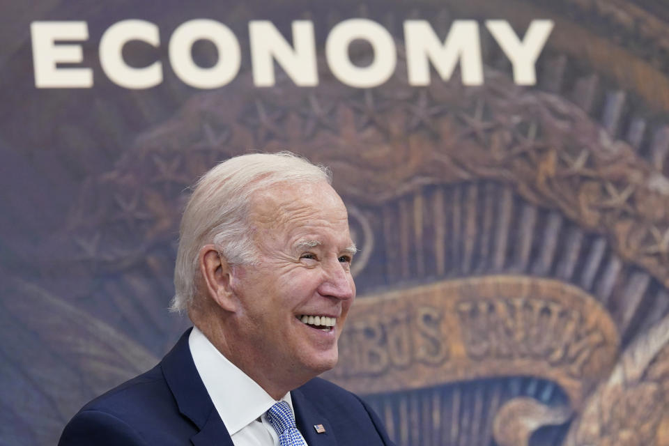 President Biden is all smiles, with a large screen saying Economy projected behind him.