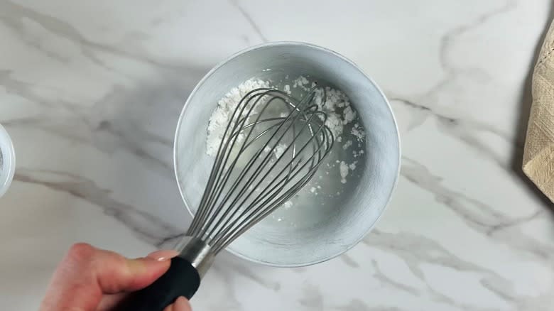 hand whisking water and cornstarch