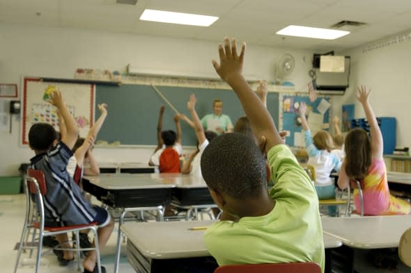 Kids in a classroom responding to the teacher's question. There are 11 kids in this shot, but the focus is on the one child in t