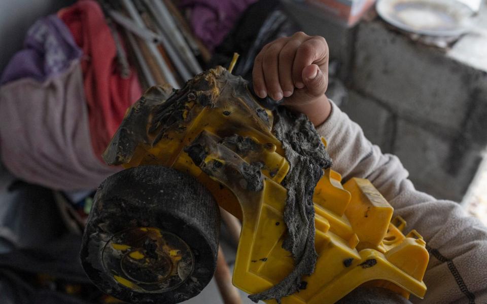 A young British child shows a toy truck which was melted when his tent burned down in Roj camp, northeast Syria - Sam Tarling for The Telegraph