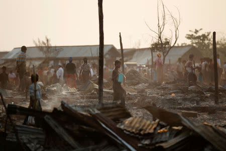 People stand among debris after fire destroyed shelters at a camp for internally displaced Rohingya Muslims in the western Rakhine State near Sittwe, Myanmar May 3, 2016. REUTERS/Soe Zeya Tun