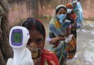 An election officer checks the temperature of a voter before allowing voters to pass at a polling station, during the first phase of state elections at Paliganj, in the eastern Indian state of Bihar, Wednesday, Oct. 28, 2020. With an overall declining coronavirus positive trend, Indian authorities decided to hold the first state legislature election since the outbreak of COVID-19. People began voting Wednesday in the country’s third largest state Bihar with of a population of about 122 million people. (AP Photo/Aftab Alam Siddiqui)