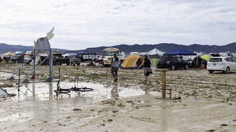 People walk in the mud after torrential rain during the Burning Man event at the temporary settlement of Black Rock City, Nevada, United States, on Sept. 2, 2023.